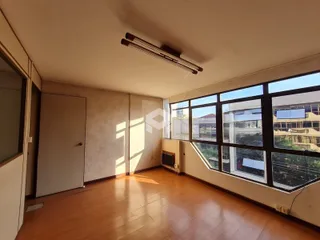 A sala possui piso de madeira e grandes janelas com vista.