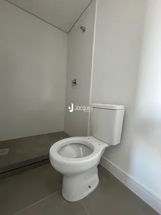Um banheiro com paredes brancas e piso de cerâmica claro.