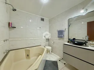 Foto de um banheiro com banheira e revestimento de azulejos brancos.