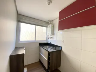 Vista interna de uma área de cozinha com revestimento de azulejo branco e piso de madeira.