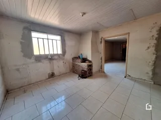 Interior de uma sala com paredes de reboco exposto e piso de cerâmica.