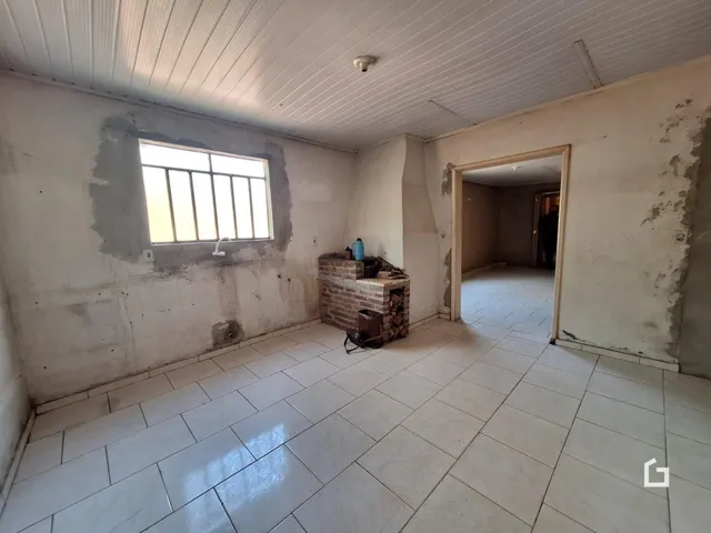 Interior de uma sala com paredes de reboco exposto e piso de cerâmica.