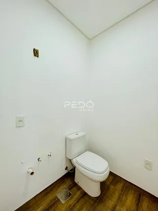 Foto interna de um banheiro com piso de madeira e paredes brancas.