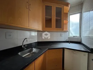 Foto de uma cozinha com armários de madeira e bancada escura.