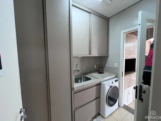 Foto de uma área de cozinha com armários cinzas e máquina de lavar roupa.