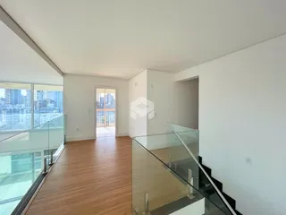 Vista de um corredor interno com piso de madeira e grandes janelas.