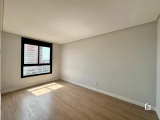 Uma sala de estar com piso de madeira clara e grande janela.