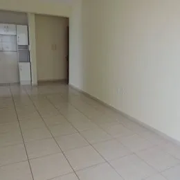 Vista de um corredor com piso de cerâmica claro e paredes brancas.