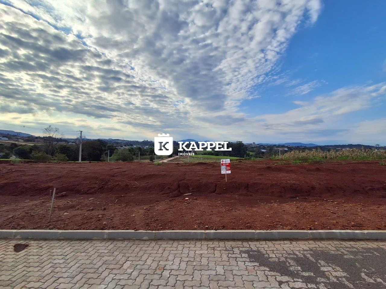Vista ampla de terra vermelha e paisagem com colinas ao fundo.
