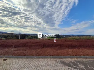 Vista ampla de terra vermelha e paisagem com colinas ao fundo.
