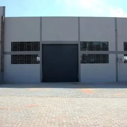 Fachada externa de um imóvel com porta de garagem cinza.