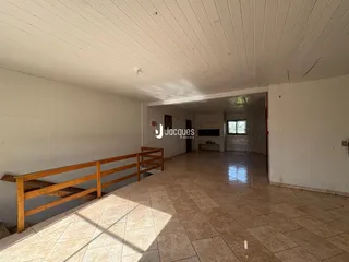 Hall de entrada com piso de cerâmica e corrimão de madeira em um imóvel no Brasil.