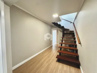 Foto de um corredor interno com piso de madeira e escadaria.