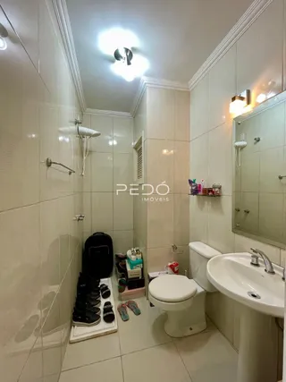 Foto de um banheiro com azulejos brancos e louças sanitárias.