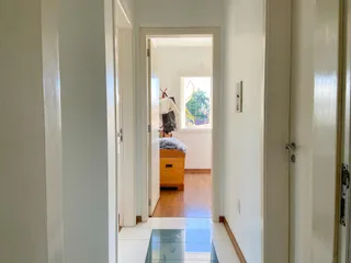 Um corredor interno com portas brancas e piso claro.