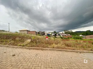 Vista externa de uma propriedade com terreno gramado sob um céu nublado.