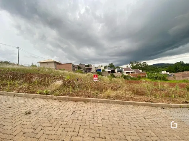 Vista externa de uma propriedade com terreno gramado sob um céu nublado.