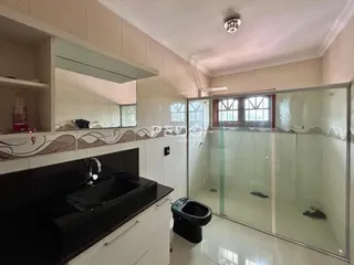 Foto de um banheiro com box de vidro e revestimento cerâmico.