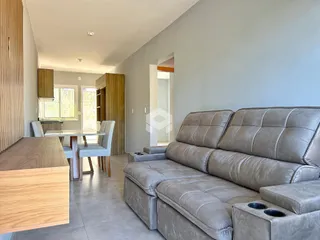 Sala de estar com sofá grande e mesa de jantar em um apartamento.