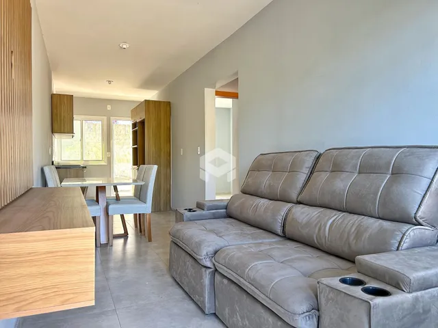Sala de estar com sofá grande e mesa de jantar em um apartamento.