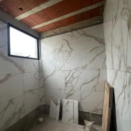 Parede interna revestida com azulejos de mármore branco.