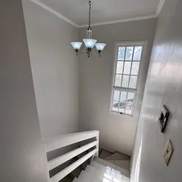 Foto de um corredor interno com paredes brancas e uma janela.