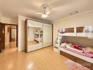 Quarto com armário embutido e cama de madeira no interior da residência.