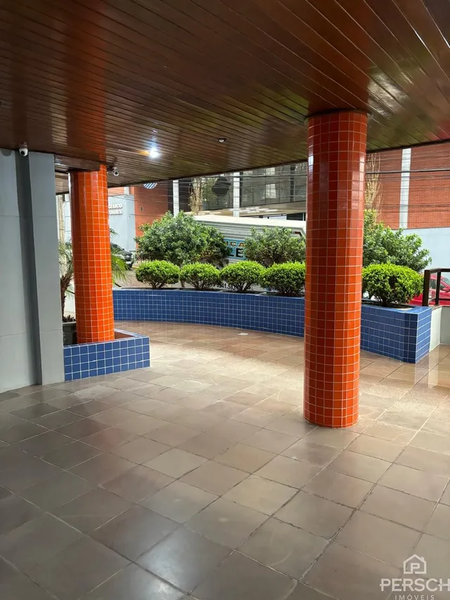 Área coberta com piso de cerâmica e colunas de tijolo laranja em um imóvel em Lajeado.