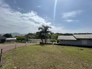 Vista externa de um terreno com gramado e estruturas ao fundo.