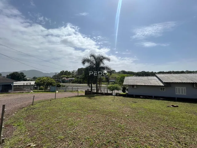 Vista externa de um terreno com gramado e estruturas ao fundo.