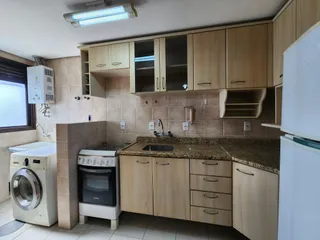 Cozinha com armários de madeira clara e bancada de granito.