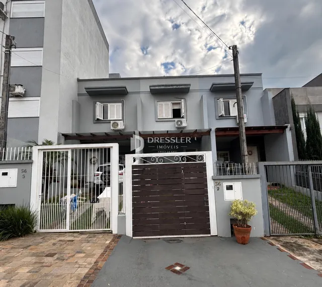 Fachada de uma residência em Lajeado, Brasil, com portão de ferro e detalhes arquitetônicos.