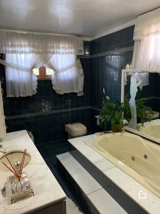 Foto de um banheiro com banheira e azulejos escuros.