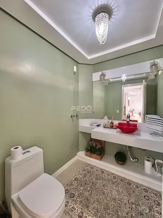 Foto de um banheiro com paredes verde-claro e louças brancas.