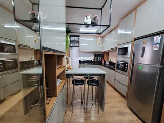 Interior de uma cozinha moderna com armários brancos e piso de madeira clara.