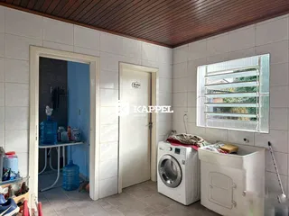 Foto de um cômodo com máquina de lavar e janela, apresentando paredes claras e piso de cerâmica.