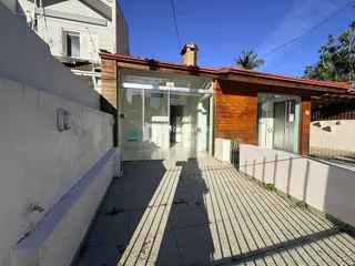 Fachada de uma residência com porta de vidro e piso de cerâmica no exterior.