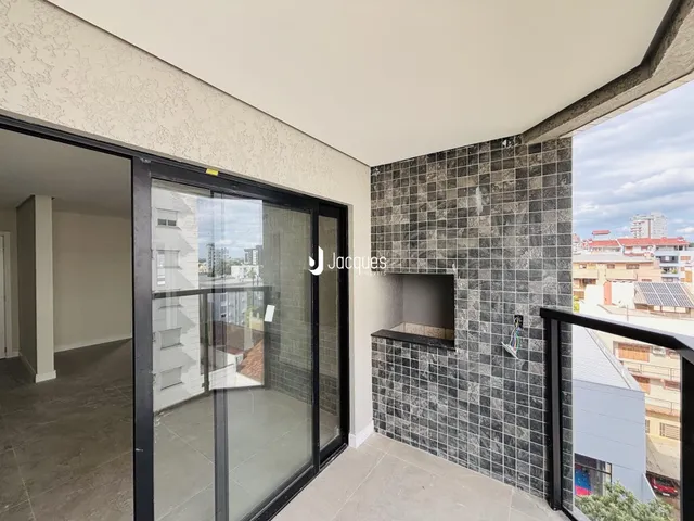 Interior de um apartamento com porta de vidro abrindo para uma varanda com revestimento de cerâmica escura.