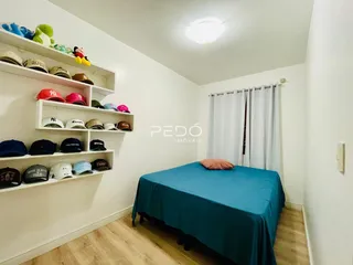 Quarto com cama e prateleiras brancas em um ambiente claro.