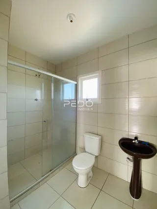 Banheiro com revestimento cerâmico e box de vidro.