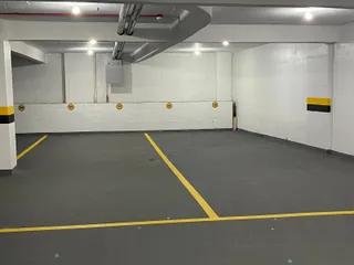 Foto de uma área interna com piso de concreto e marcações amarelas.