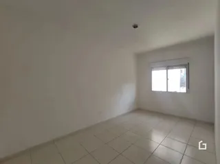 Vista interna de uma sala com paredes brancas e piso de cerâmica.