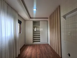 Ambiente interno com piso de madeira e cortinas brancas.