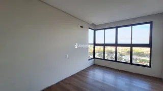 Ambiente interno com piso de madeira e grande janela de vista para a paisagem.