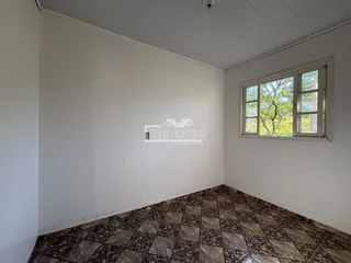 Imagem de um cômodo interno com paredes brancas e piso de ladrilhos escuros.