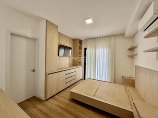 Quarto com cabeceira e armários em madeira clara.