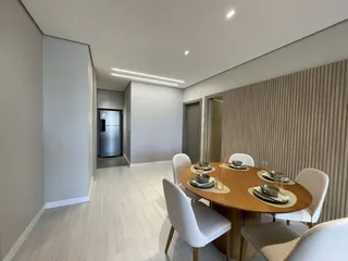 Sala de jantar com mesa de madeira e cadeiras em um apartamento.