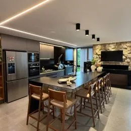 Cozinha moderna com bancada escura e eletrodomésticos de aço inoxidável.