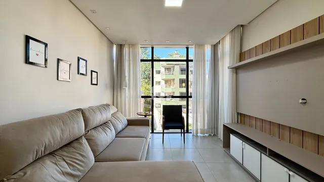 Sala de estar com sofá e portas de vidro que dão para a vista.