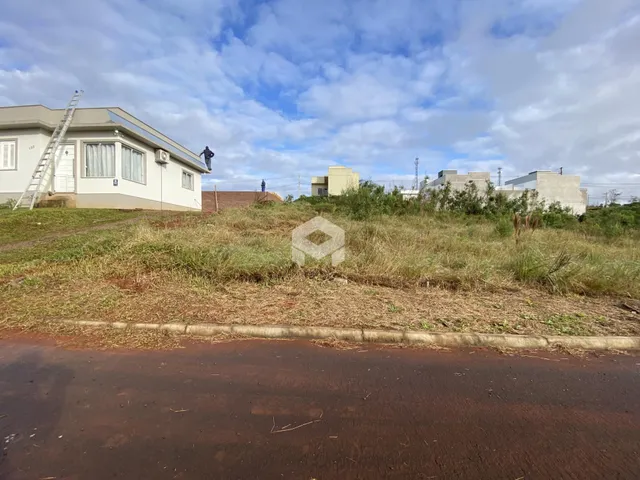 Vista externa de uma propriedade com terreno gramado e construções ao fundo.